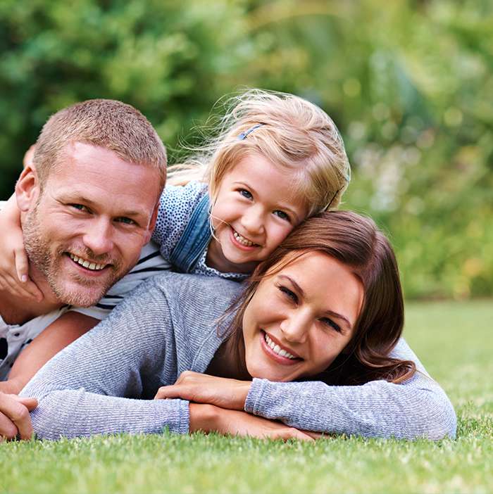 Family of three laying on grass smiling