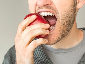 a dental implant patient biting into an apple