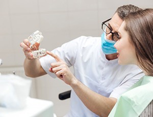 a dentist showing a patient a model of dental implants