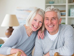 elderly couple smiling and wearing matching gray sweaters 