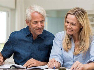 Older man and woman smiling and looking at paperwork
