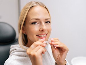 Woman smiling while holding clear aligner