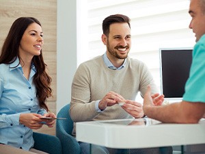 Dentist and couple talking in dental office