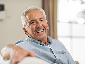 A smiling, older man happy with his new implant dentures