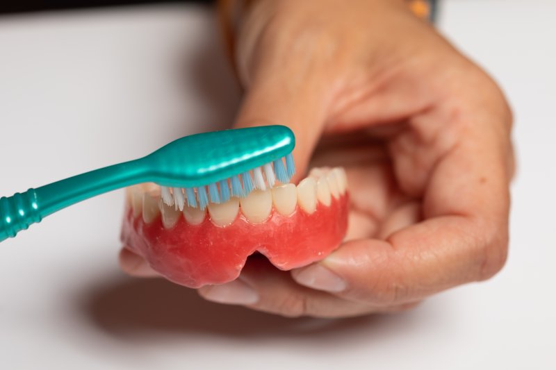 patient cleaning dentures with a toothbrush