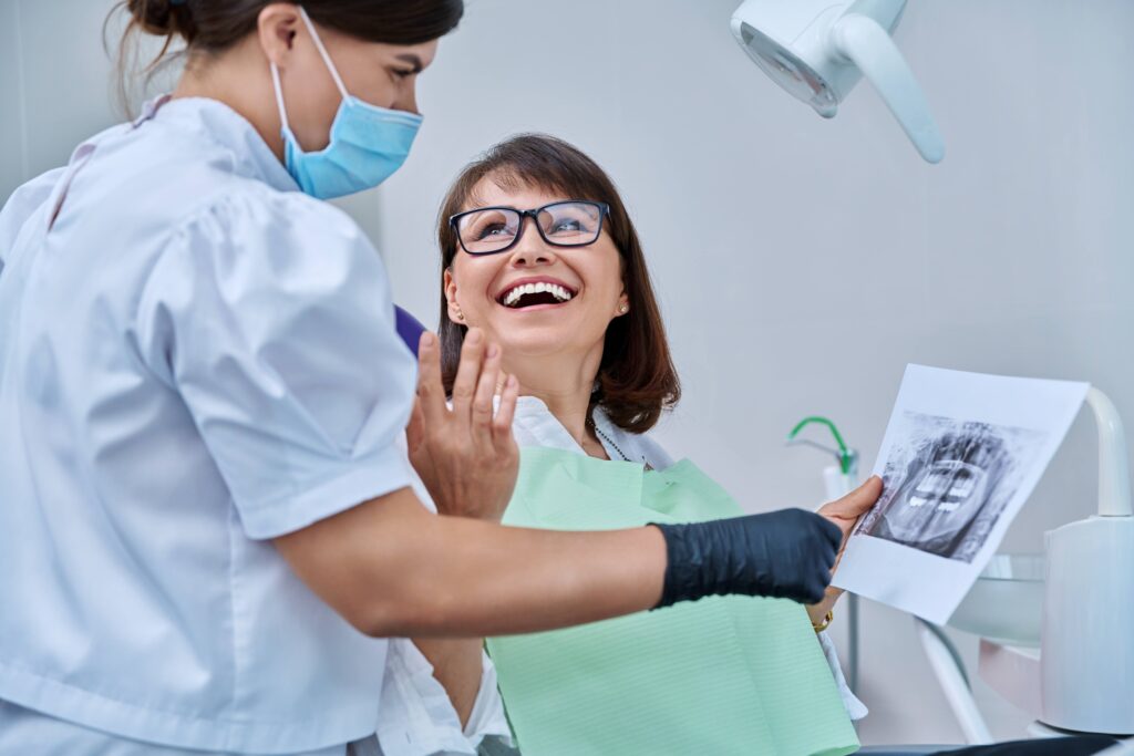 Woman smiling at dentist holding X-ray